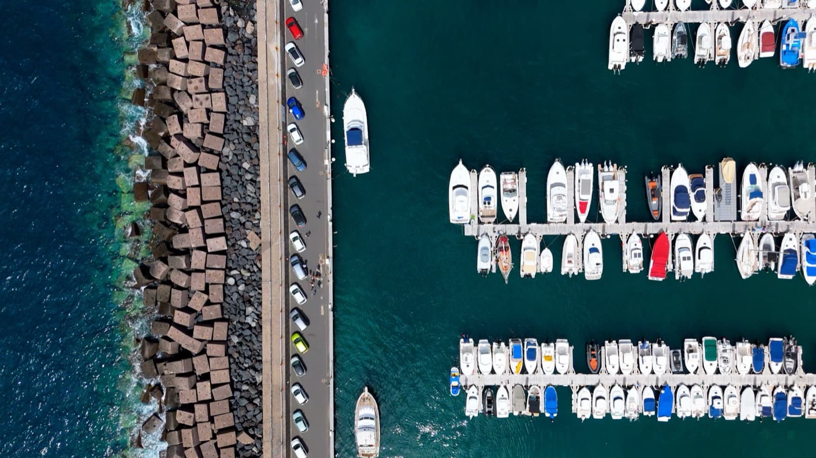 Jachthaven met boten naast een pier en golfbreker, recht van boven