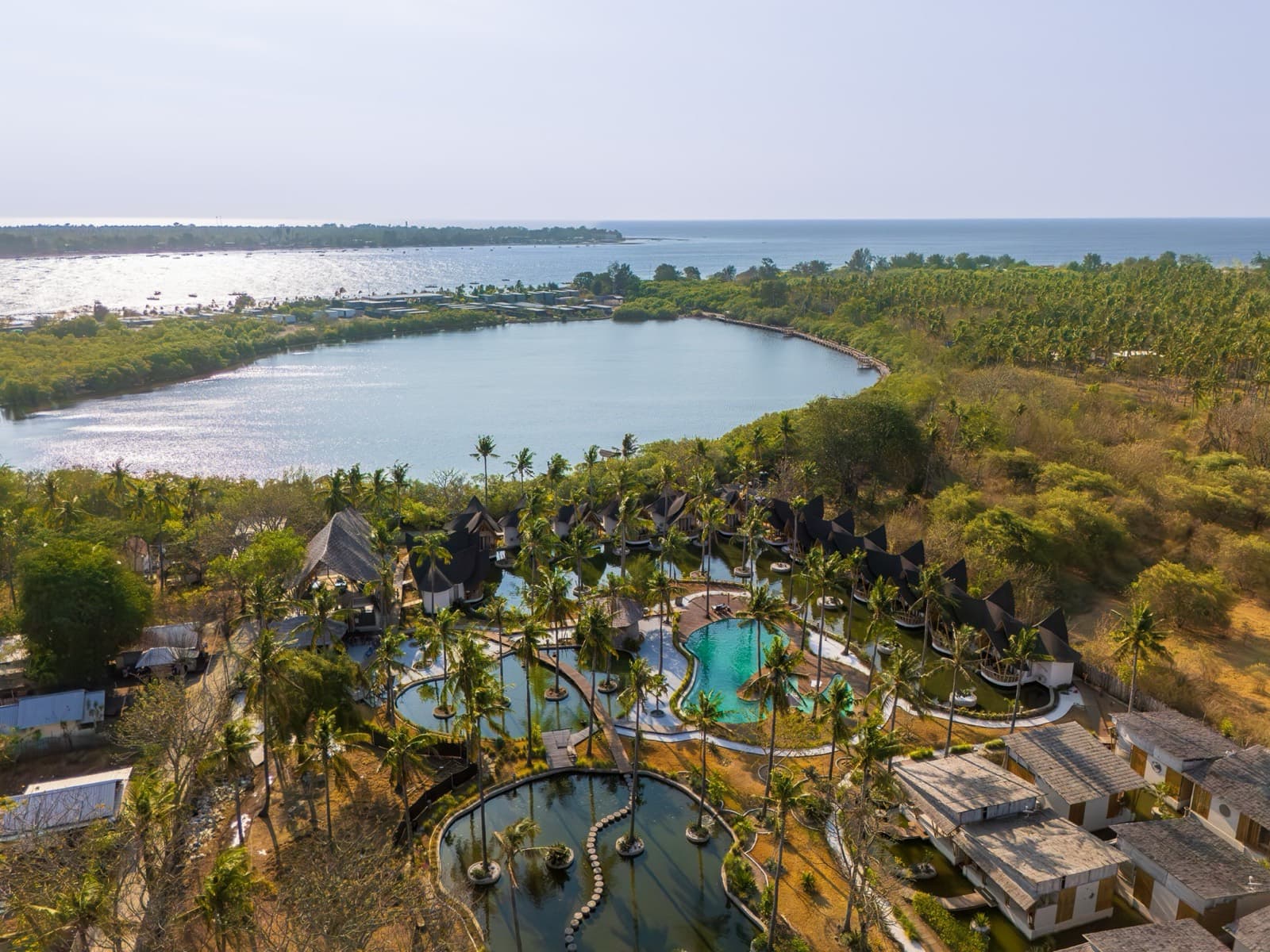 Resort met zwembaden tussen palmbomen aan een meer