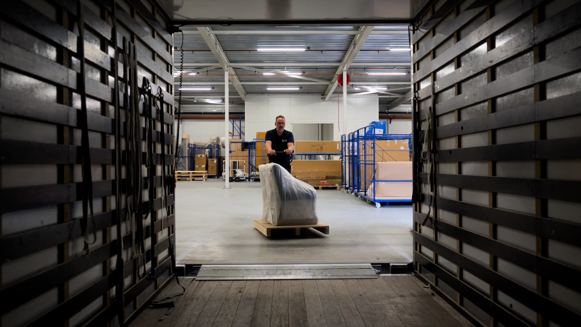 Medewerker rijdt een ingepakt meubelstuk naar de vrachtwagen