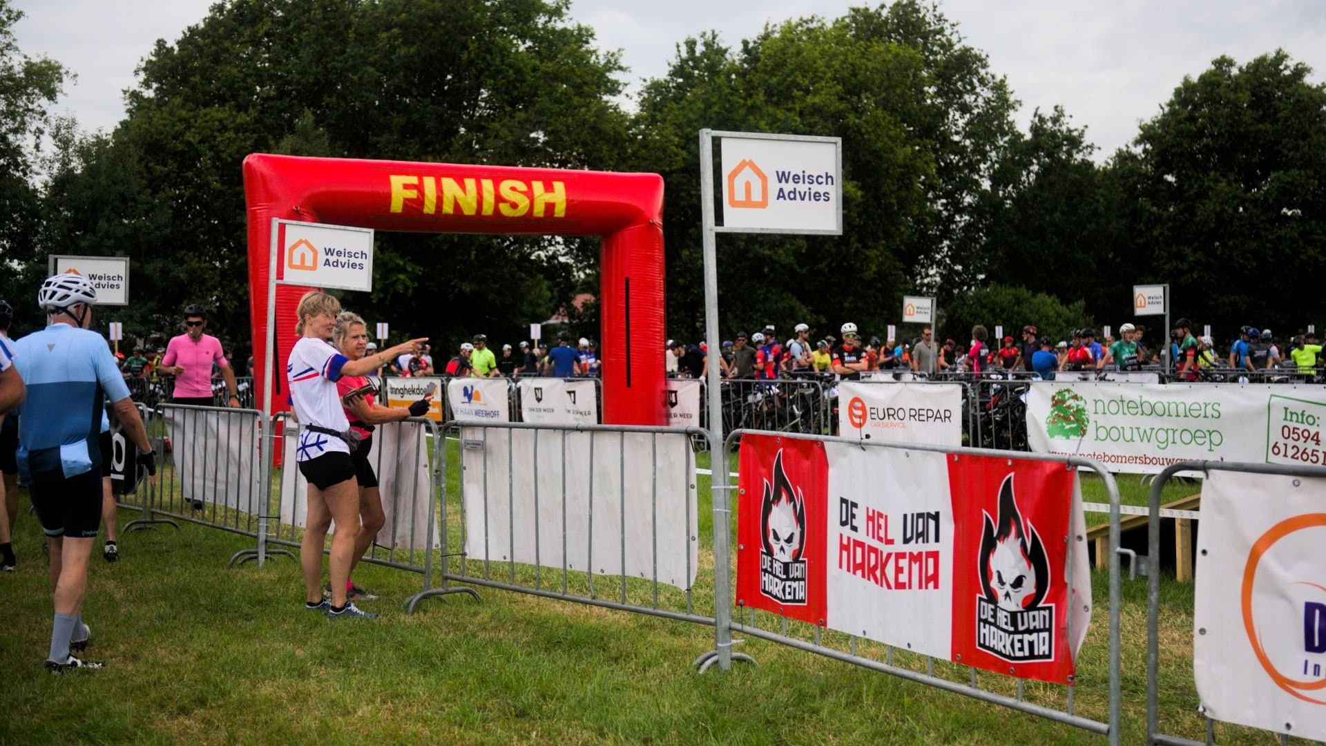 Deelnemers bij de finishboog tussen de sponsorborden