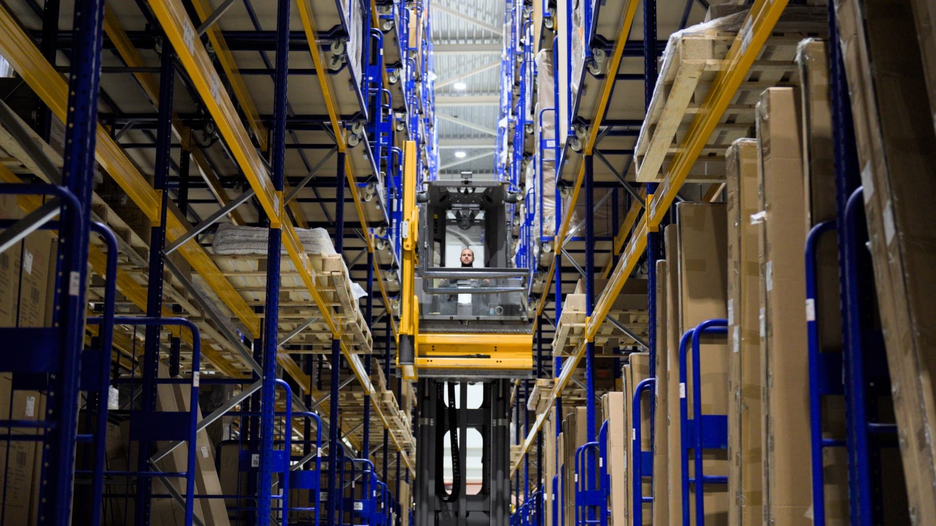 Heftruck tussen de hoge stellingen in het magazijn van Kapenga