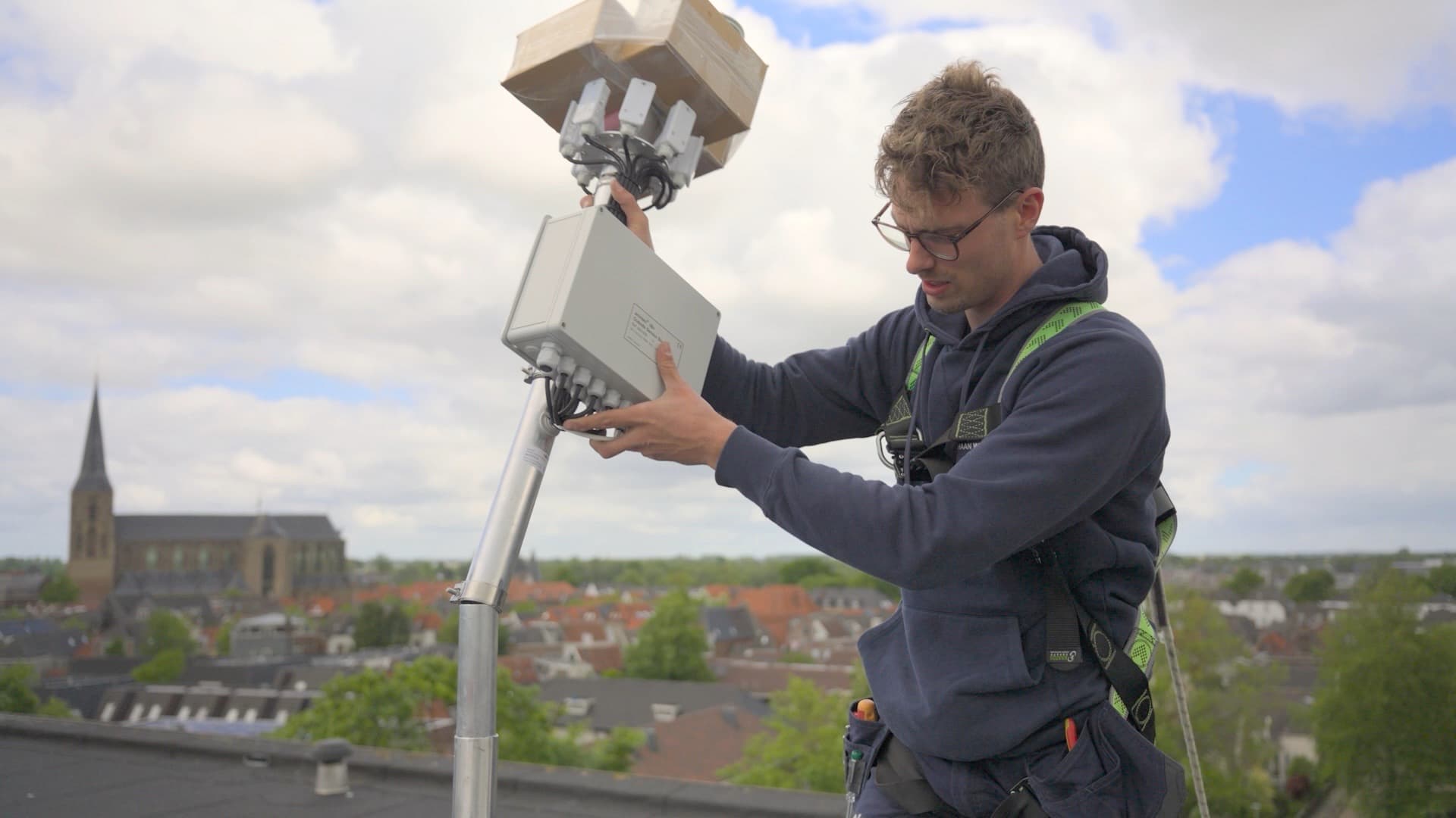 Elektricien monteert apparatuur op een dak boven de stad