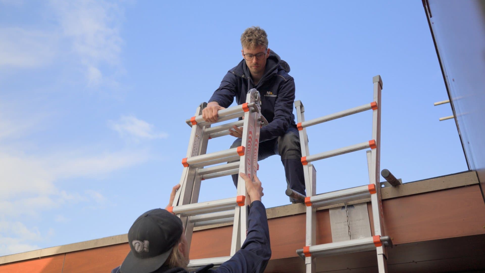 Collega's geven een ladder door naar het dak