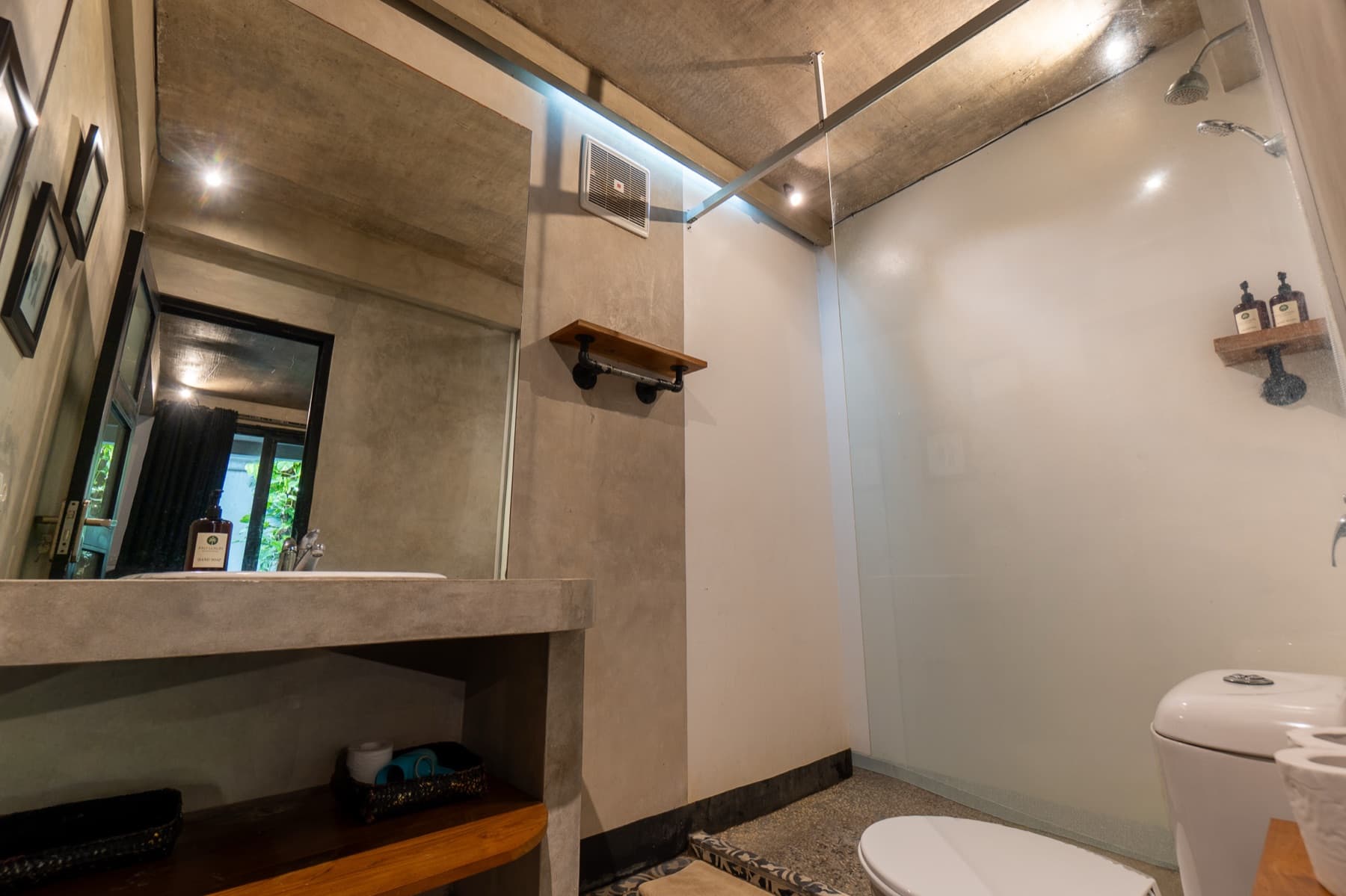 Badkamer met betonnen wastafel, spiegel en inloopdouche