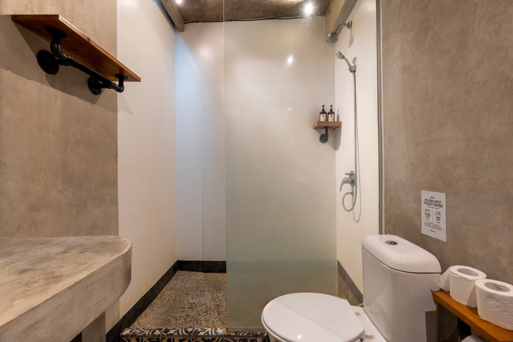 Badkamer met douche achter glas en houten plank